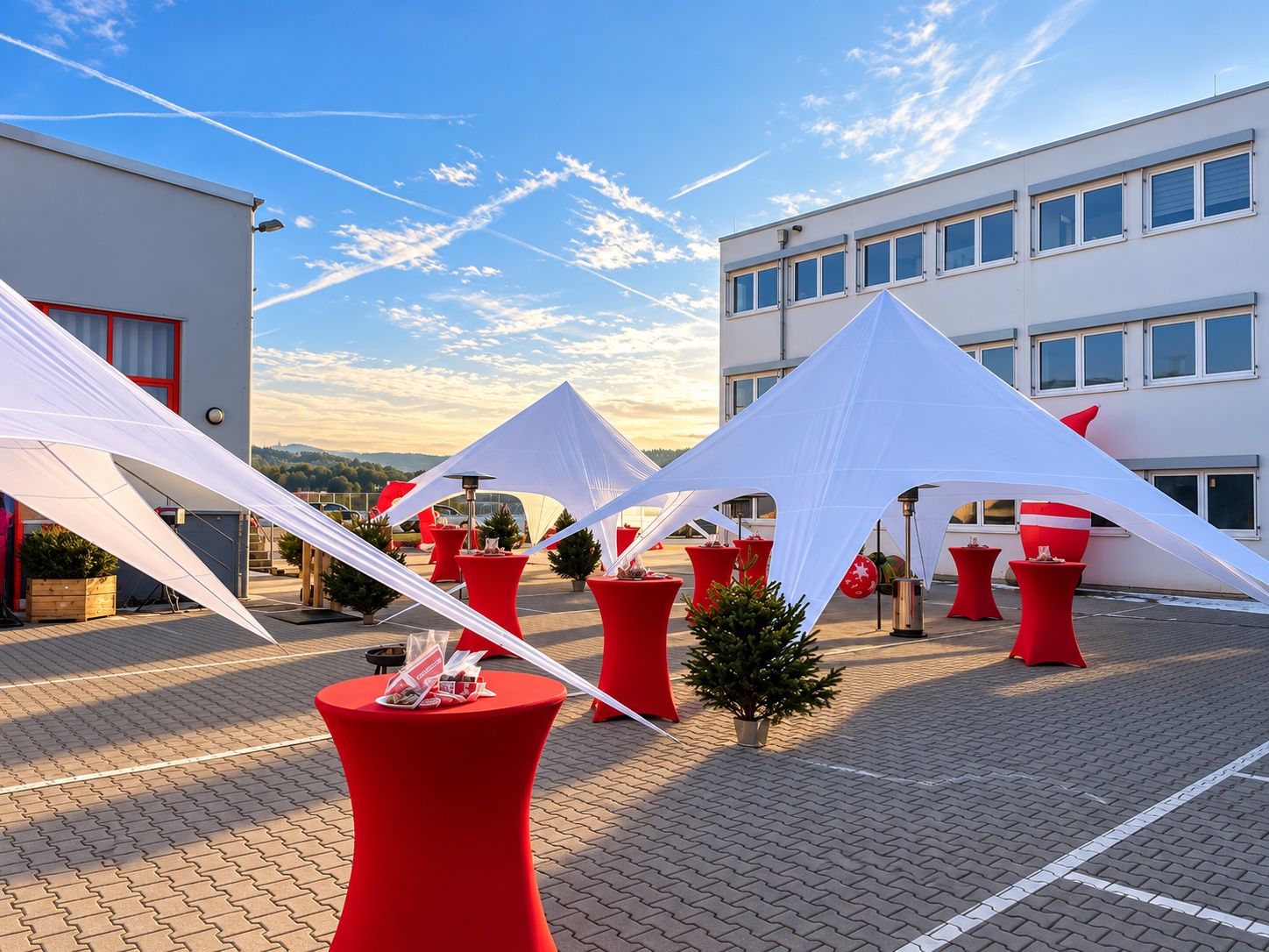Firmenevent im Hof mit weißen Sternzelten, roten Stehtischen und kleinen Tannenbäumen bei Abendsonne