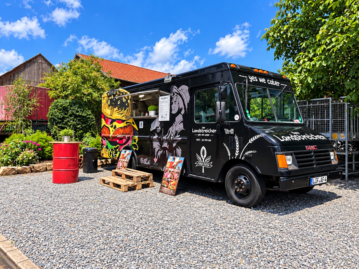Der schwarze Landstreicher-Foodtruck mit Burger-Graffiti auf einem Kiesplatz bei blauem Himmel