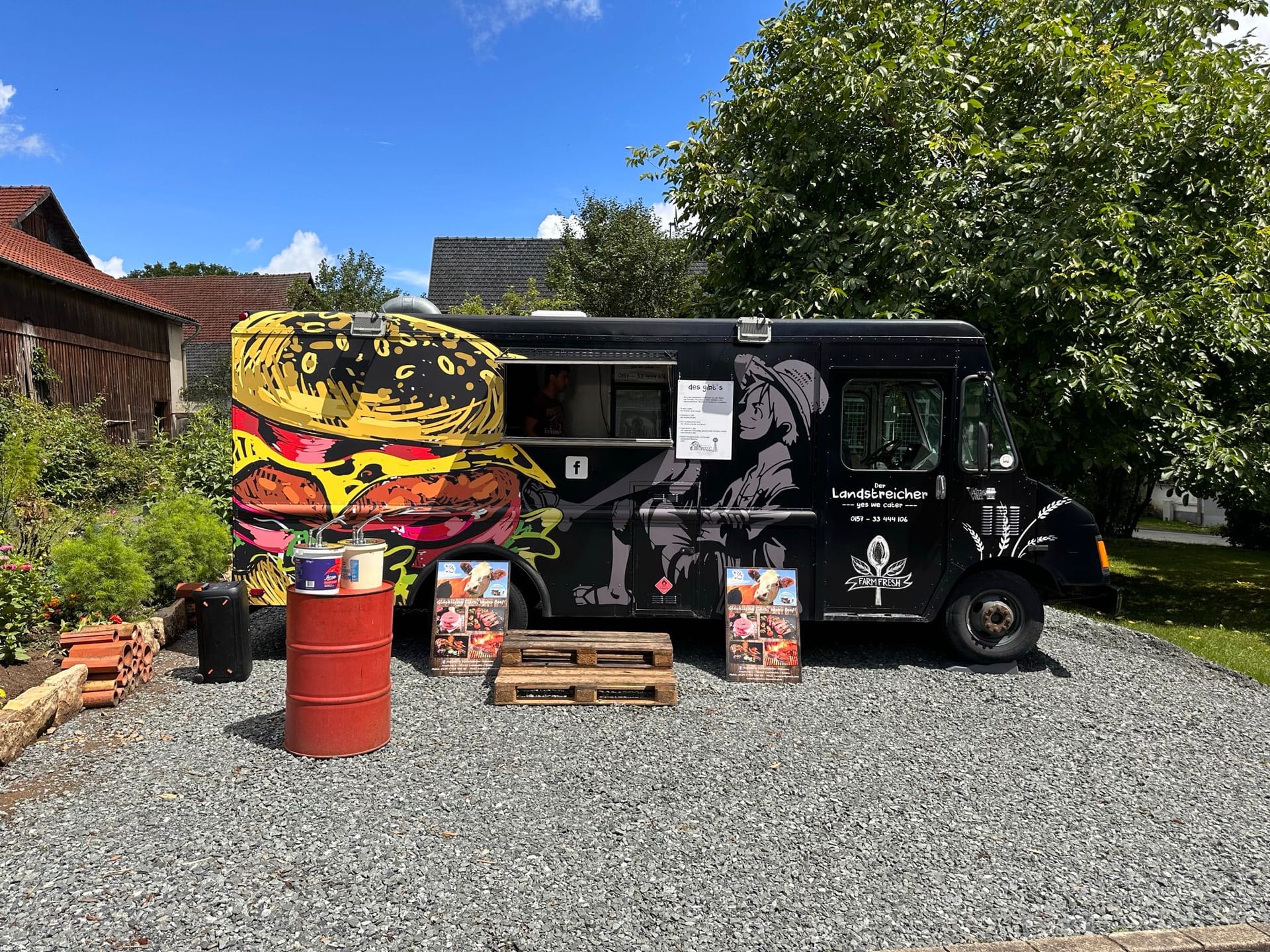 Schwarzer Landstreicher-Foodtruck mit großem Burger-Graffiti von der Seite